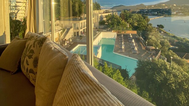 A room with a large window overlooking a pool and a view of a cityscape. - Best View-Stylish Penthouse with communal pool (Kerkira)