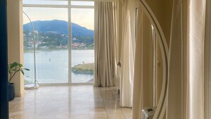 A spacious room with a large arched window, a view of a body of water, and a potted plant. - Best View-Stylish Penthouse with communal pool (Kerkira)
