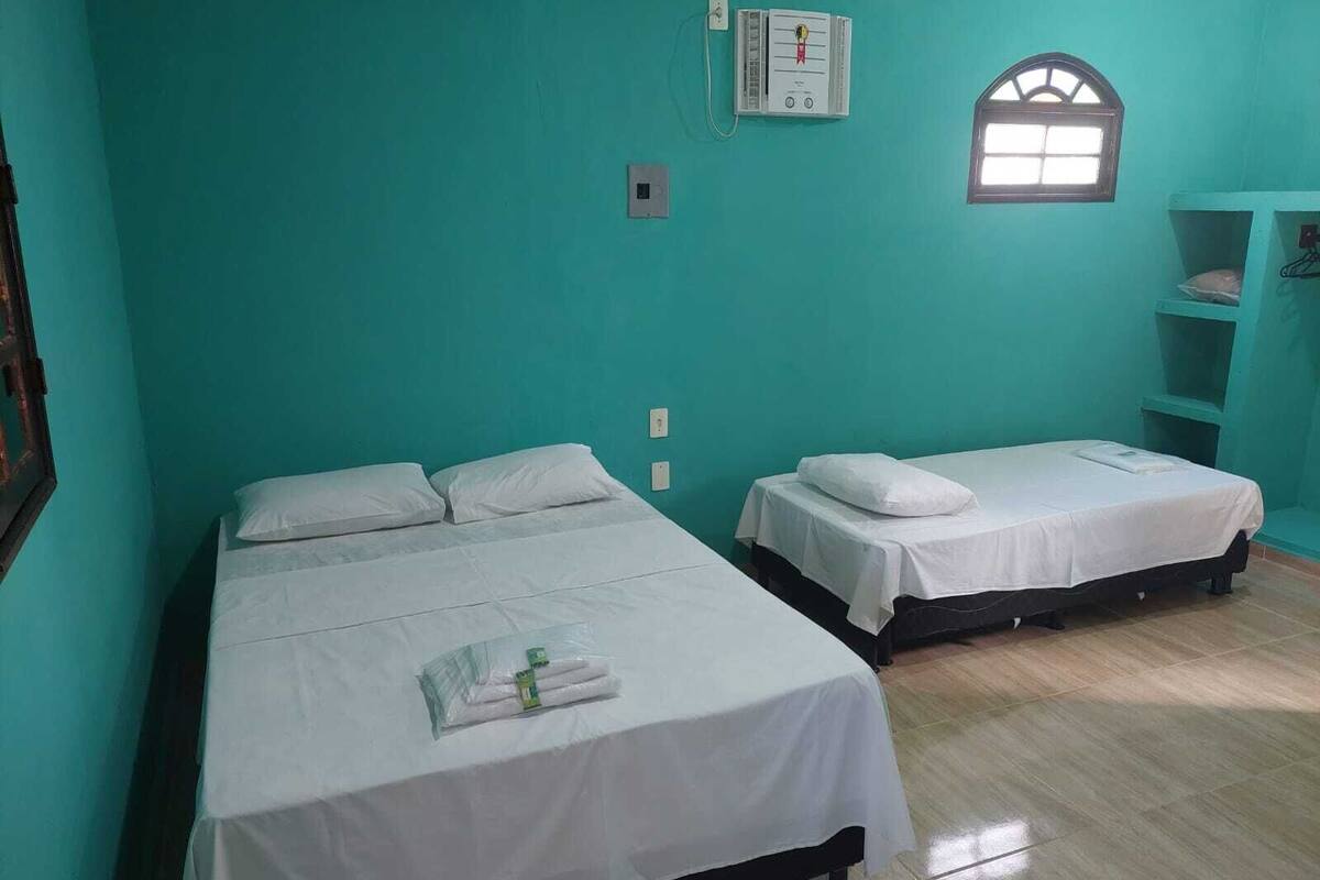 A room with two beds, a window, and a wall-mounted thermostat.