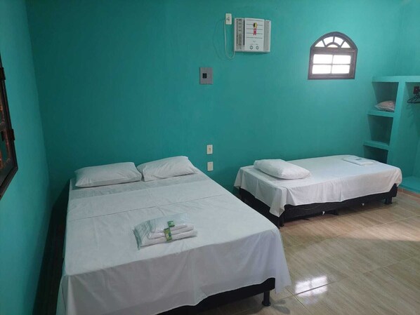 A room with two beds, a window, and a wall-mounted thermostat.