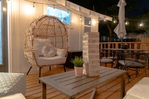 An outdoor seating area with a woven chair, a table, and a stack of white blocks. - Dreamy Getaway 2br&2ba, Relaxing Backyard w/ Mural (Memphis)