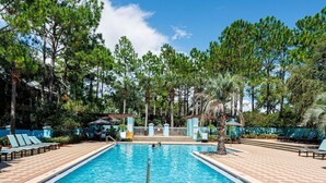Una piscina con sillas de descanso y palmeras.