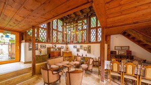 A spacious living room with wooden beams, a fireplace, and a dining area with wooden chairs. - Serbetci Garden Konak (Safranbolu)