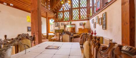 Une salle à manger traditionnelle en bois, avec une longue table, des chaises et un plafond haut orné de poutres en bois.