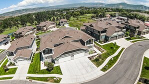 A residential area with modern houses, a curved driveway, and a view of distant mountains.