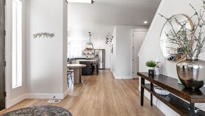 A modern kitchen with a central island, wooden flooring, and a dining area with a round table and chairs.