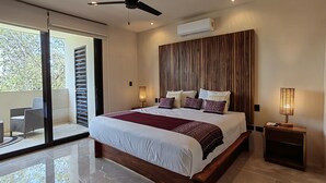 A modern bedroom with a large bed, a ceiling fan, an air conditioning unit, and a balcony with a view of trees. - ITZÁ ALDEA ZAMÁ - BOHO CHIC con Alberca (Tulum)