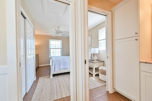 Relax in this serene bedroom with a large bed, ceiling fan, and a cozy nightstand with a lamp.