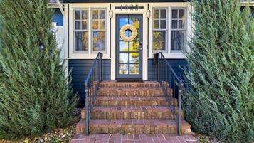 A house with a number 1025 on the front door, a brick staircase leading up to the entrance, and a wreath hanging on the door.