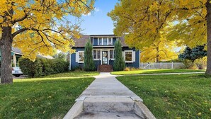 A two-story house with a front yard, a pathway leading to the front door, and a white picket fence. - Vintage Modern near Downtown - Arcade Machine (Rapid City)