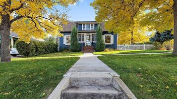 A two-story house with a front yard, a pathway leading to the front door, and a white picket fence.