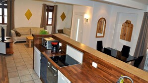 A modern kitchen with a wooden countertop, built-in appliances, and a dining area with a table and chairs.