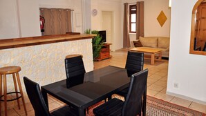A dining area with a stone accent wall, a wooden bar, and a sofa in the background.