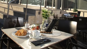 An outdoor dining area with a table set for breakfast, including croissants and coffee, in front of a building with a sign reading "LA PARADA". - Hostal La Parada (Getafe)