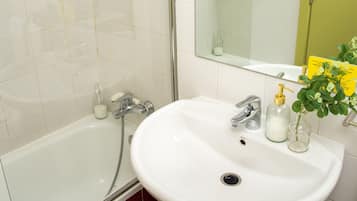 Een badkamer met een wit wastafelmeubel, een douchecabine met glazen wanden en een spiegel met een gele deur.