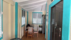 A compact room with teal-painted walls, a wooden dining table, two chairs, and a refrigerator. - The Place at the Sea (Ponce)