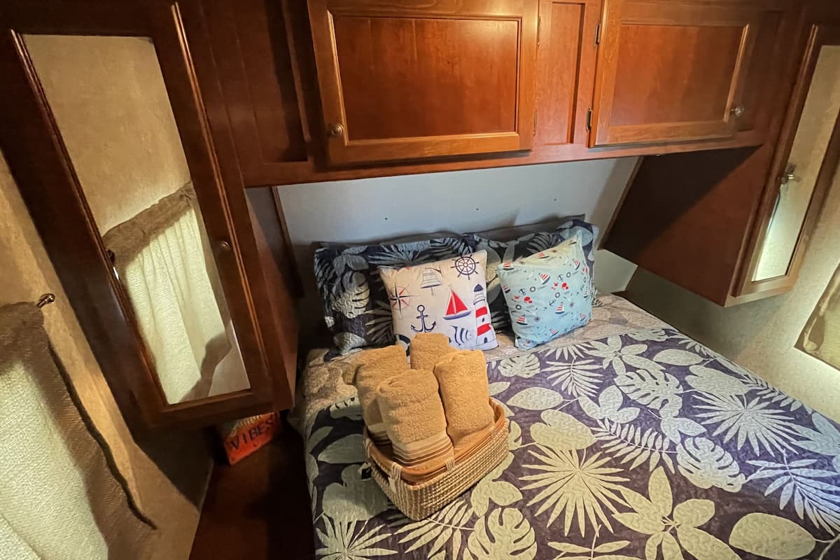 A compact bedroom with a bed, pillows, and a small stack of towels.