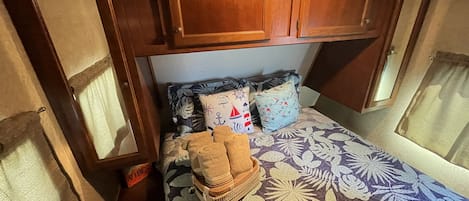 Una habitación compacta con cama, almohadas y una pequeña pila de toallas.