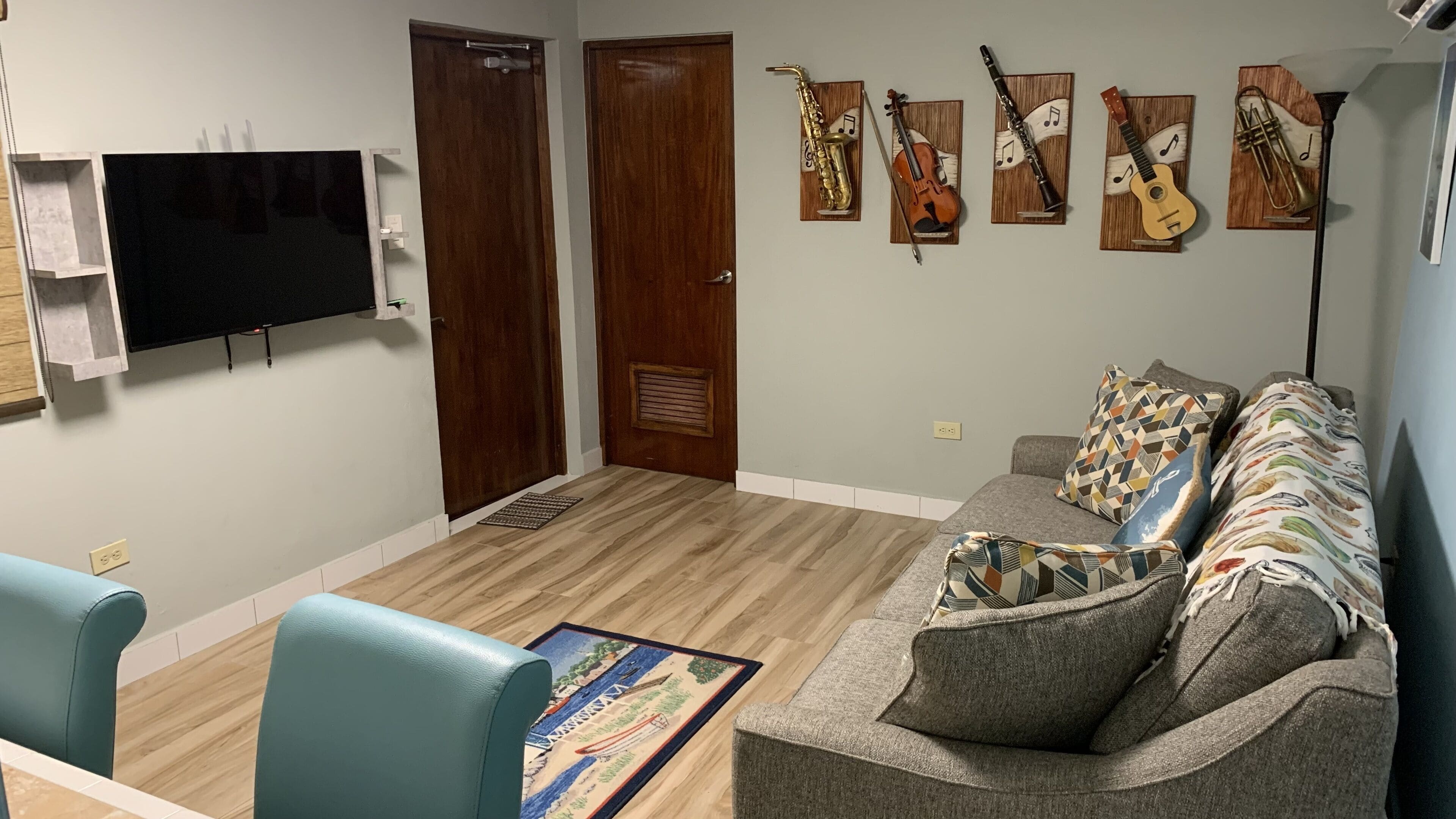 Ein Wohnzimmer mit einer Couch, einem Fernseher und an der Wand befestigten Musikinstrumenten.