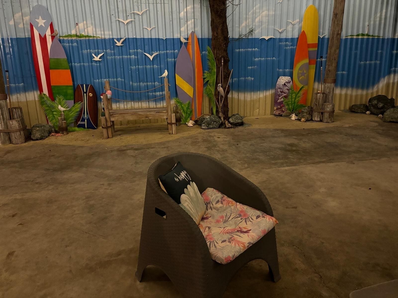 A beach-themed room with a chair, surfboards, and a mural of the ocean.