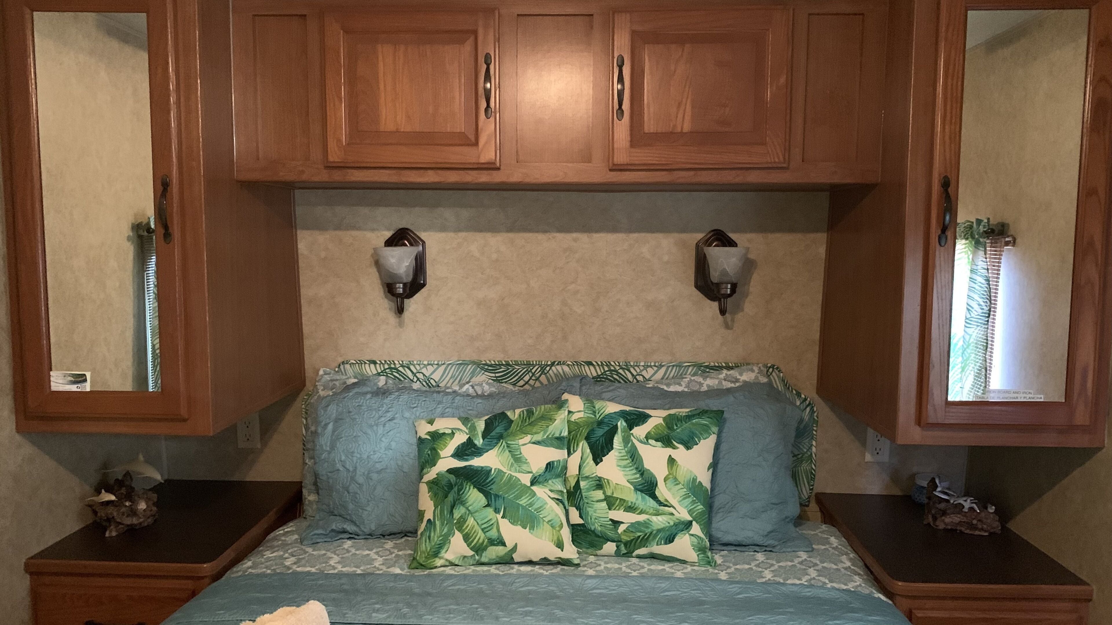A bedroom with a bed, two nightstands, wooden cabinets, and wall-mounted lights.