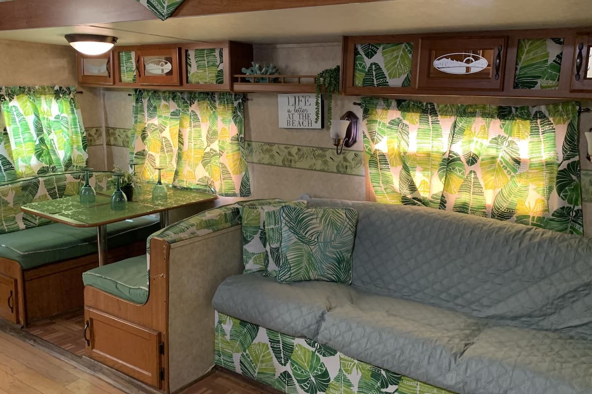 A cozy RV interior with a dining area, seating, and a wall-mounted light fixture.
