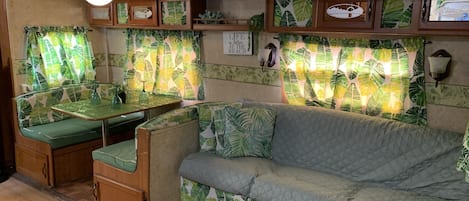 A cozy RV interior with a dining area, seating, and a wall-mounted light fixture.