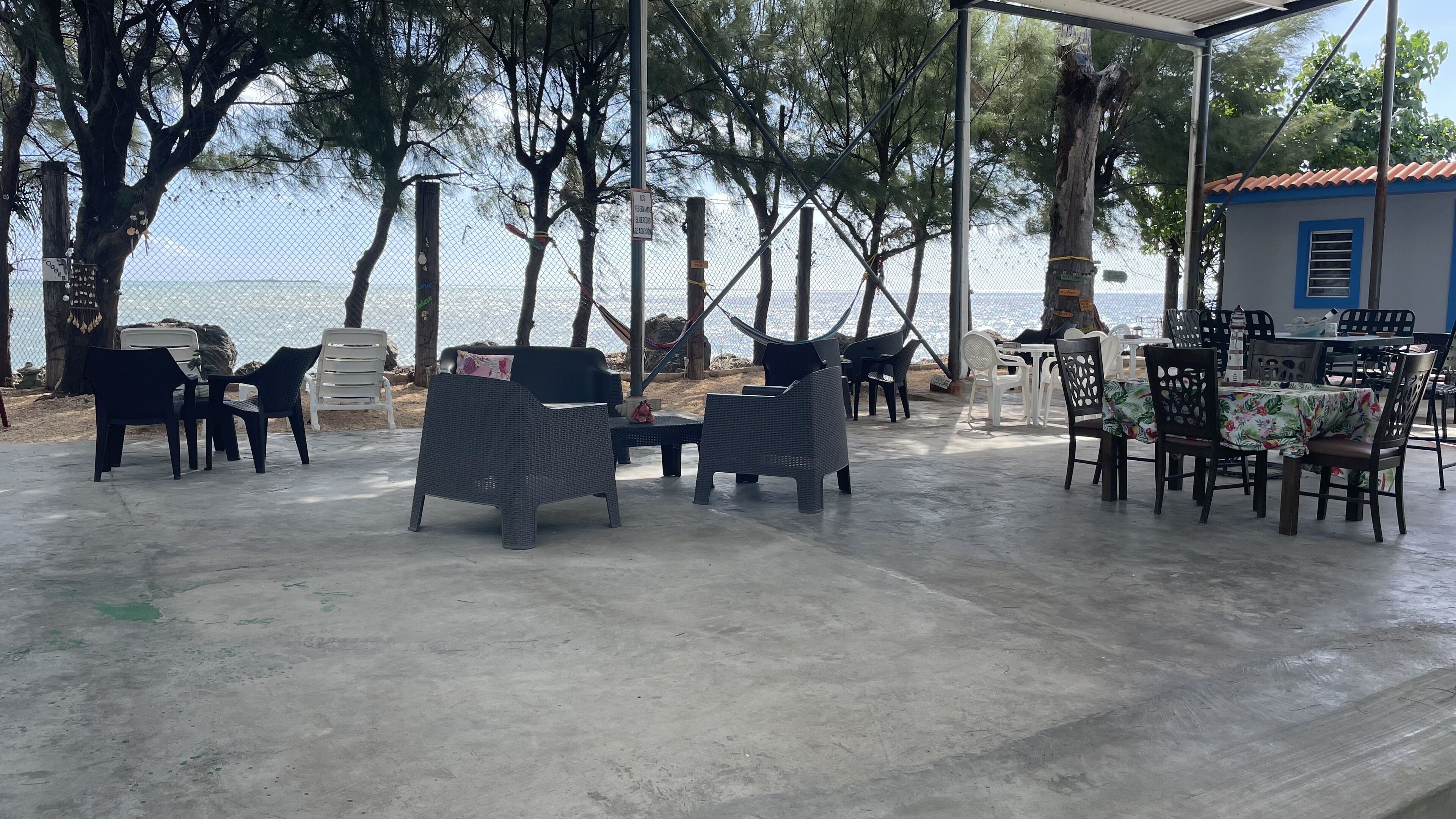 Un espace extérieur aménagé avec des meubles en osier et offrant une vue sur la mer.