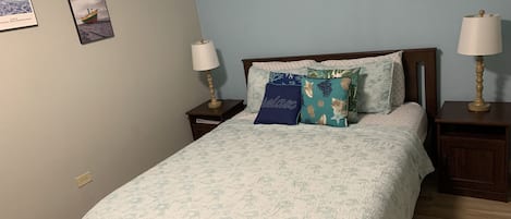 A bedroom with a bed, two nightstands, two wall-mounted lamps, and two framed pictures on the wall.
