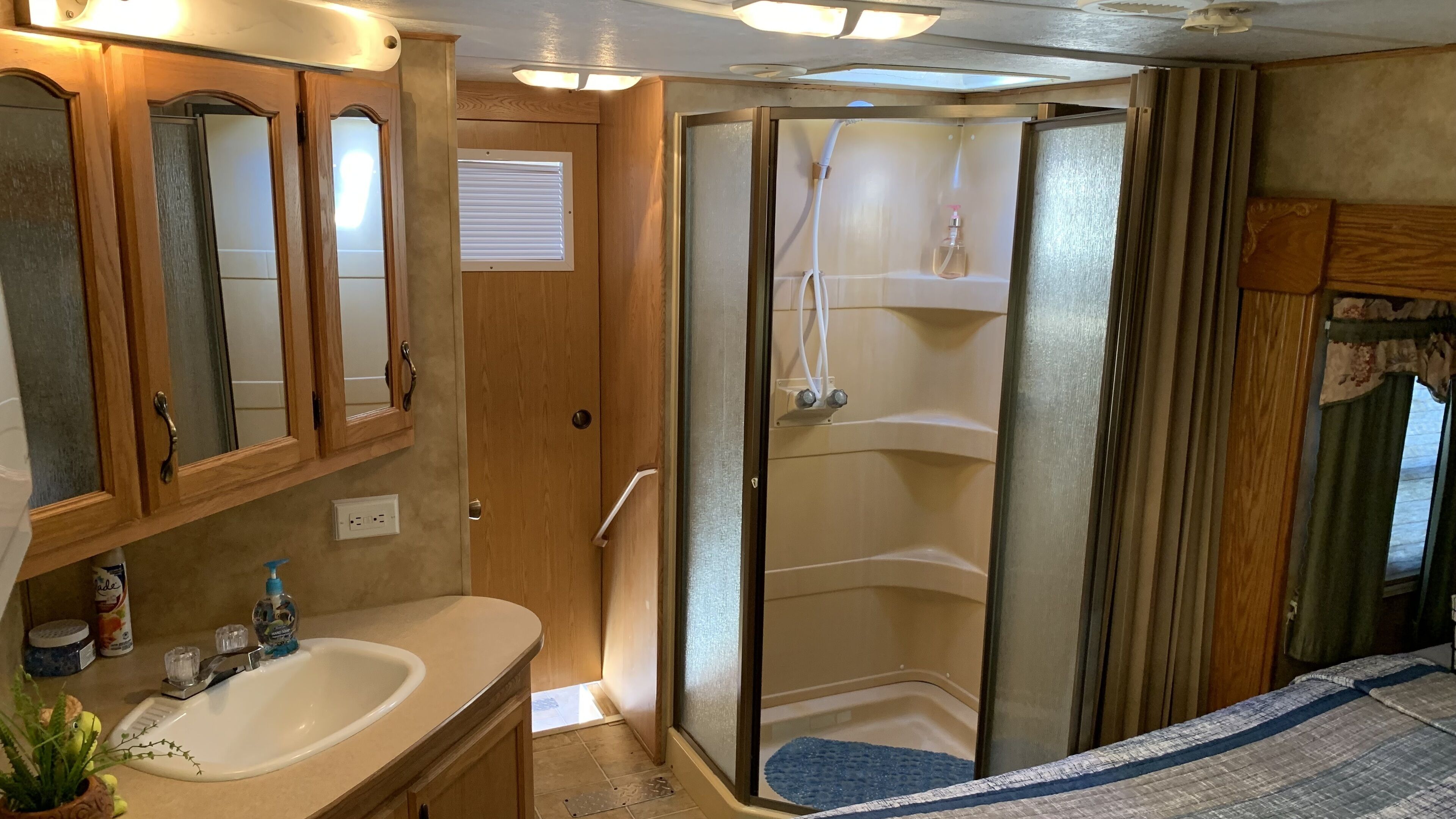 Ein kleines Badezimmer für Wohnmobile mit Dusche, Waschbecken und Spiegel.