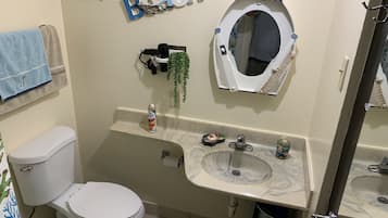 A bathroom with a toilet, a sink with a marble countertop, a mirror, and a towel rack with a blue towel.