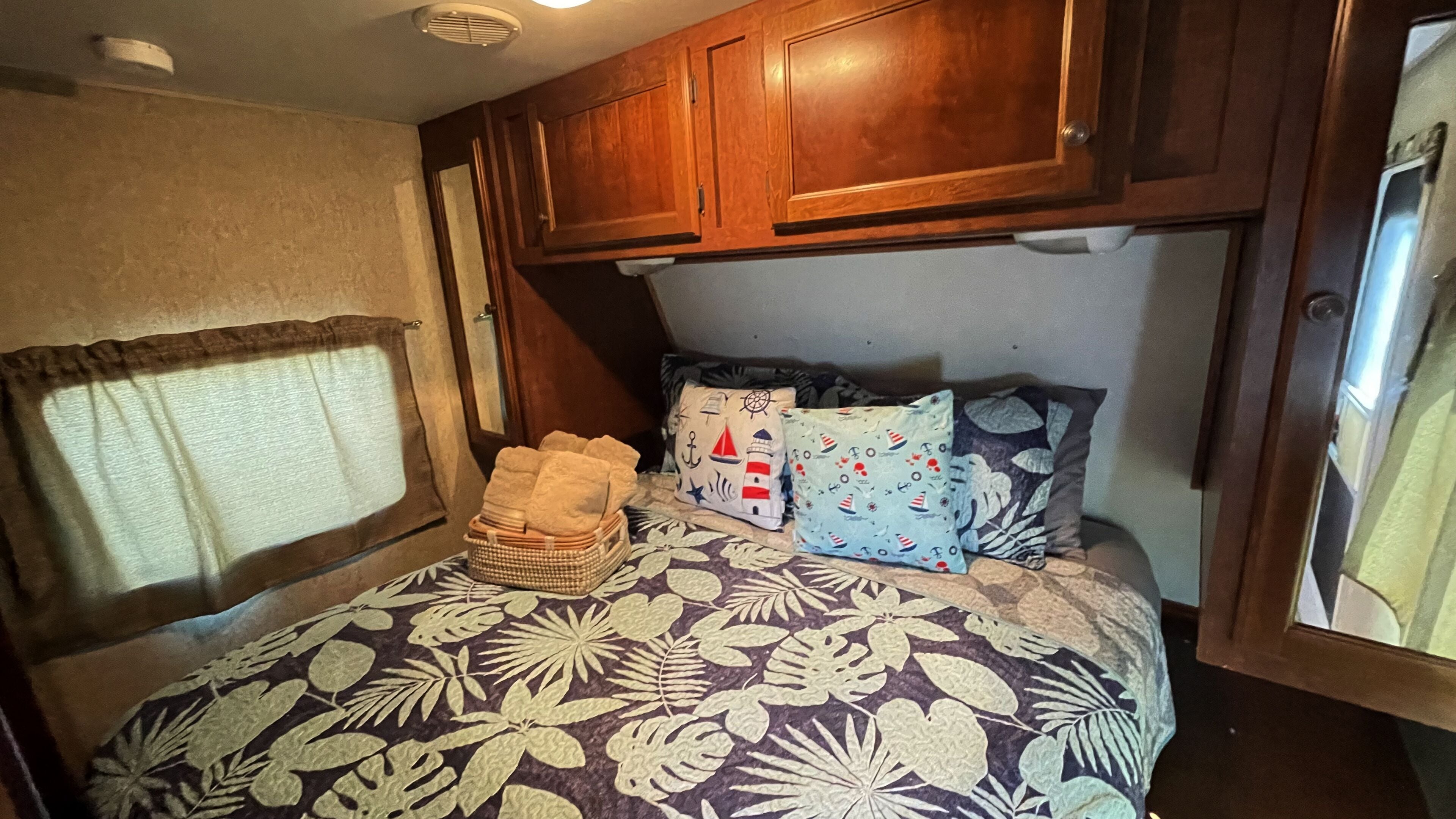 Een slaapkamer met een bed, kussens, een mand en houten kasten.