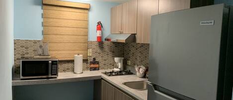 Una cocina compacta equipada con microondas, cafetera y refrigerador.