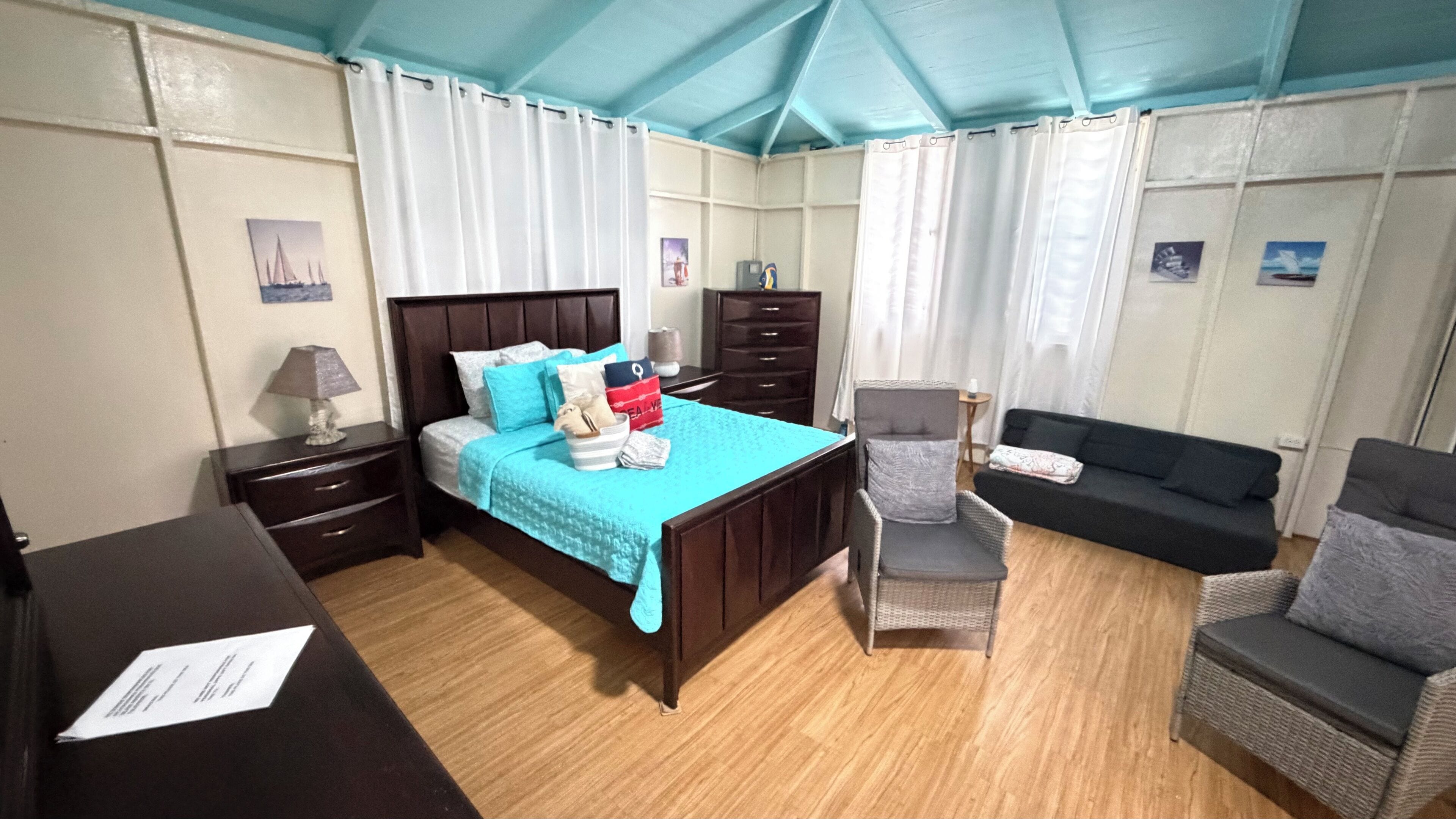 A room with a bed, a chair, a sofa, and a desk.