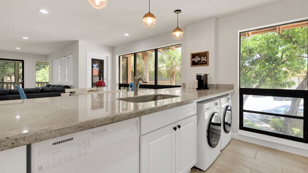 A modern kitchen with a large island, built-in appliances, and large windows offering views of the outdoors.