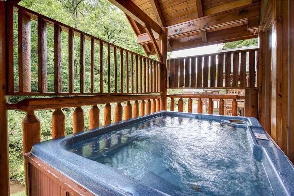 Ein Whirlpool auf einer Holzterrasse mit Blick auf Bäume.