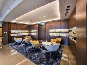 A modern lobby with a seating area, a reception desk, and wall-mounted shelves with decorative items. - Charming 2BR Apt at Opera Grand (Dubai)
