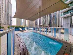 A rooftop pool with water jets, surrounded by high-rise buildings. - Charming 2BR Apt at Opera Grand (Dubai)