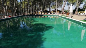 A rectangular swimming pool surrounded by trees and wooden structures. - Camping Green Village Pin Tourist (Palagiano)