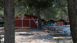 A campground with picnic tables, a red building labeled 'Minicamp', and a covered area with blue chairs. - Camping Green Village Pin Tourist (Palagiano)