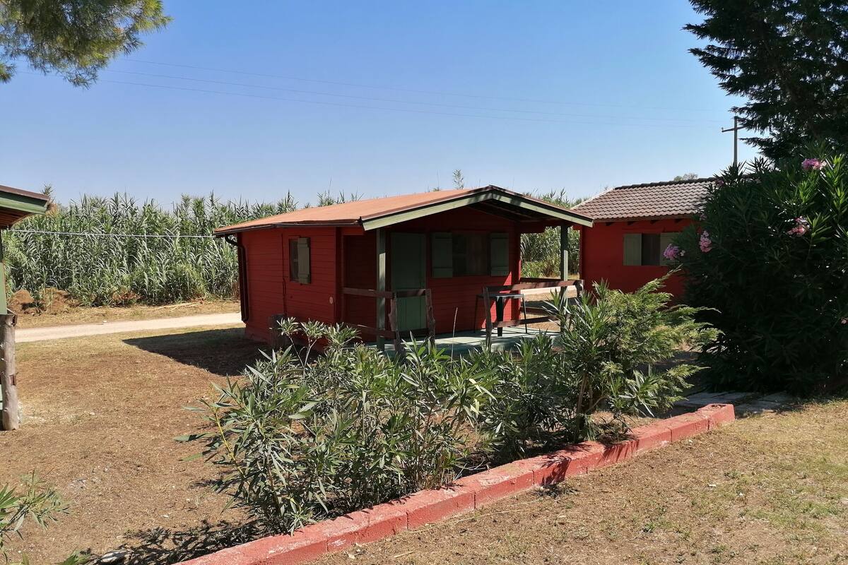 Een rood gebouw met een veranda en een bank.