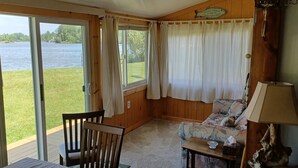 Une pièce avec vue sur un lac, comprenant une chaise, une table et une lampe.