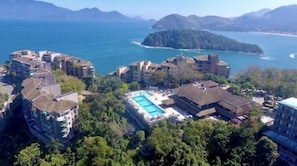Una località balneare con diversi edifici, una piscina e vista sul mare e sulle montagne.