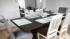 Ruokailutila, jossa on musta pöytä, valkoiset tuolit ja raidalliset aluslakanat.