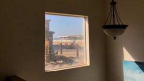 Ein Zimmer mit Fensterblick auf eine Baustelle, einer Hängelampe und einem Teil eines Bildes an der Wand.