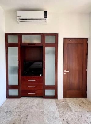 Una habitación con mueble empotrado para entretenimiento, una puerta y piso de baldosas.