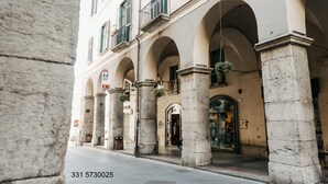 Um edifício com janelas em arco e colunas, entrada visível e plantas pendentes.