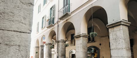 A building with arched windows and columns, a visible entrance, and hanging plants.