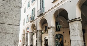 A building with arched windows and columns, a visible entrance, and hanging plants.
