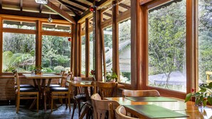 A wooden interior with large windows, tables, and chairs.
